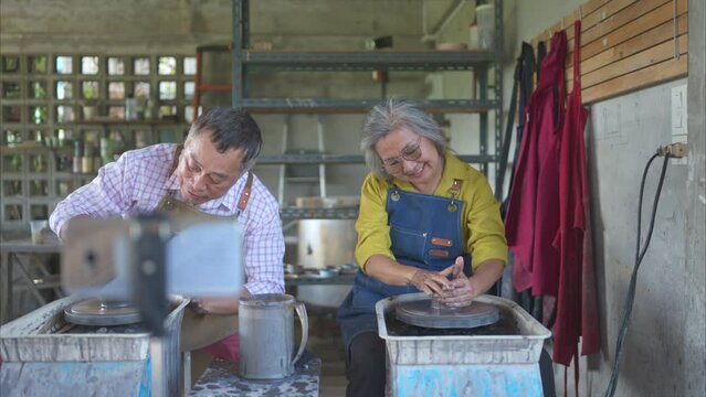 Asian retired couple with pottery making and clay painting activities in the pottery workshop with live broadcasting via social media channels