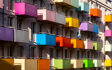 Colorful balcony parapets in yellow, green, pink, blue, orange, red, lilac, turquoise, beige, violet on the facade of an old block of flats in Tübingen, Germany. Geometric cube structures in sunlight. - obrazy, fototapety, plakaty