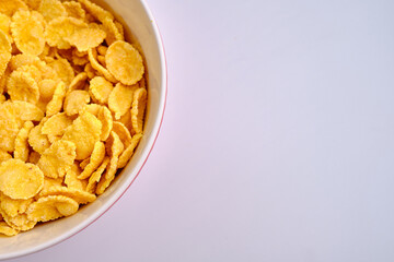 Corn flakes in a red bowl on a white background. Delicious sweet breakfast. Nutrition and health concept