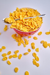 Corn flakes in a red bowl on a white background. Delicious sweet breakfast. Nutrition and health concept
