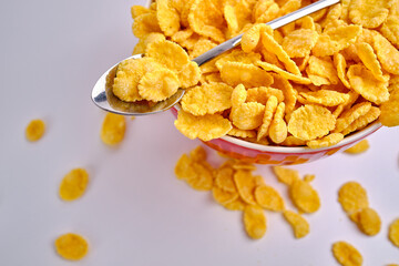 Corn flakes in a red bowl on a white background. Delicious sweet breakfast. Nutrition and health concept
