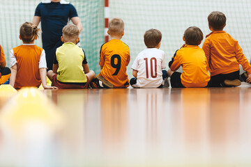Physical education class for elementary-age children. Kids sitting on the wooden court and...