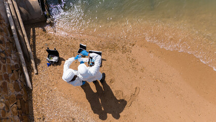 A male and female biologist are analyzing water test results and collecting samples for examination.