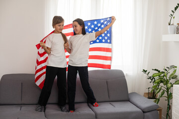 cheerful adorable kids standing under american flag and looking at camera 