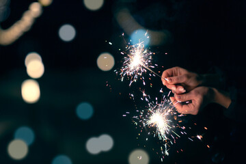 burning and sparkling sparkler at the holiday in women's hands, festive mood background