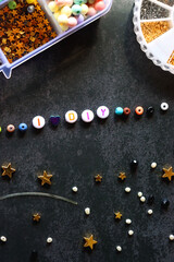 Colorful beads and various jewelry making supplies on dark background. Letter beads spelling I heart DIY. Top view.