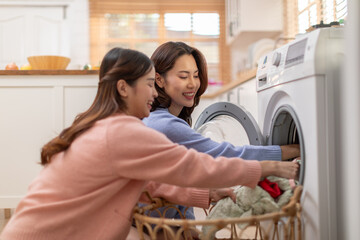 Couple LGBTQ lover doing laundry together smile and laughing. Happiness and tender moment quality time at home. LGBTQ+ Concept