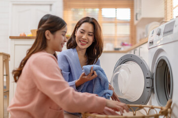 Couple LGBTQ lover doing laundry together smile and laughing. Happiness and tender moment quality...