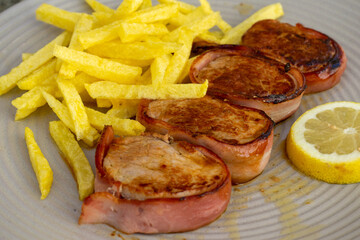 Delicious Portuguese pork tenderloin wrapped in bacon, served with crispy fries.