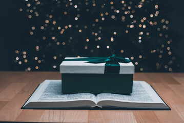 The open book of the Holy Bible. Gift. On the background is a Christmas tree. Christmas and New...