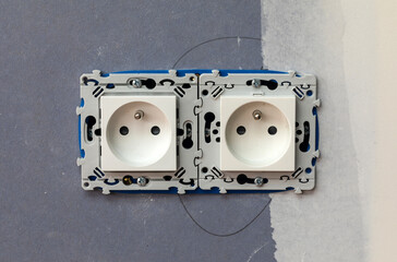 Two-slot electrical outlet socket installation on blue wallboard