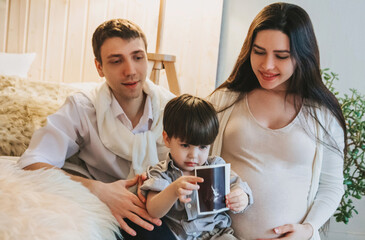 Happy family waiting for baby. Pregnant mother, father and toddler boy son with ultrasound image