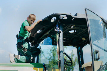Young mechanic repair tractor outdoor	
