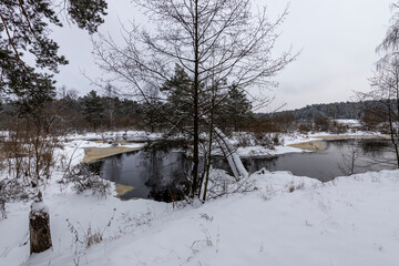 River among a snowy forest on a cloudy winter day
