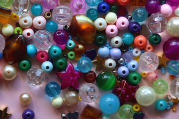 Various colorful beads on bright pink background. Top view.