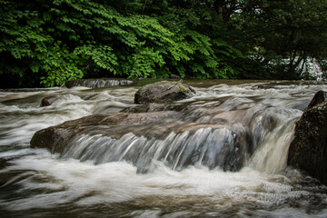 A river cascading over a collection of stones in Burrs Country Park in Bury, England.