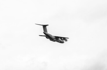 Transport plane in flight against a gray sky. - Powered by Adobe