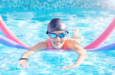 Active exercise senior woman (over age of 50) in goggles, cap doing water sport, aerobics with swim...