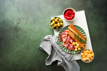 Slices of prosciutto or jamon. Delicious grissini sticks with prosciutto, cheese, rosemary, olives...
