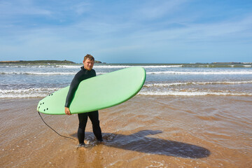 A young surfer strikes a pose with his board on the ocean's edge in Essaouira