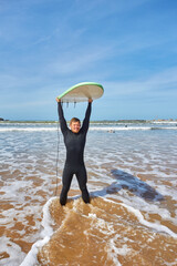 A young surfer strikes a pose with his board on the ocean's edge in Essaouira