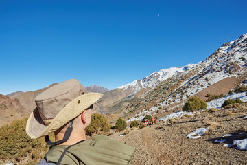 A tourist on the Atlas Mountains pass, with snow-capped peaks behind