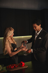 cheerful young african american man pouring red wine into glass of his attractive girlfriend