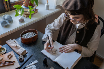 Girl paintress illustrator animator freelancer painting sketches in sketchbook sitting at desk....