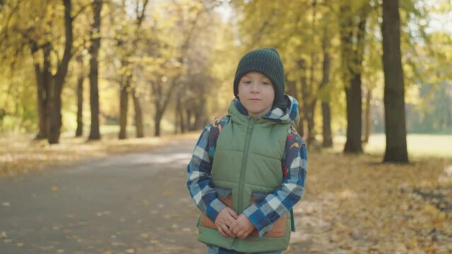Classroom Bound: Young Scholar Hurries Through Autumn Foliage. High quality 4k footage