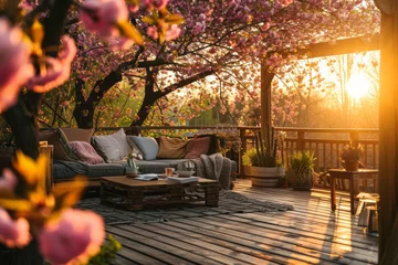 Keuken foto achterwand Tuin Cozy wooden terrace with rustic wooden furniture, soft pillows and blankets. Charming sunny evening in spring garden with blossoming trees.