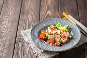 Feta cheese in cubes and vegetables - tomatoes and cucumbers in a plate. Light Greek salad with seedlings