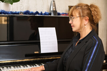 Portrait of a female pianist, music teacher sitting at grand piano in music classroom