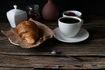 Morning with a cup of coffee and croissants. on a dark wooden background. Breakfast.