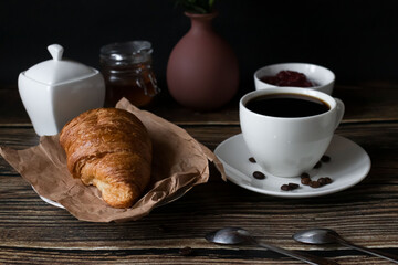 Morning with a cup of coffee and croissants. on a dark wooden background. Breakfast.