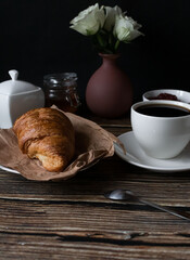 Morning with a cup of coffee and croissants. on a dark wooden background. Breakfast.