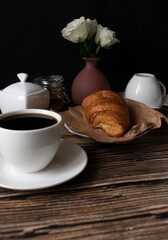 Morning with a cup of coffee and croissants. on a dark wooden background. Breakfast.