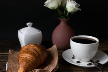 Morning with a cup of coffee and croissants. on a dark wooden background. Breakfast.