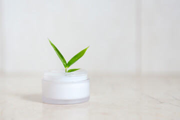 Face cream with bamboo leaves over light background