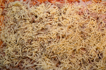Tuna and ham sprinkled with cheese on oven-ready pizza dough