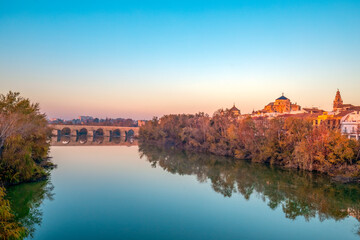 Beautiful view of the Guadalquivir River as it passes through Córdoba, Andalusia, Spain, with the Roman bridge and cathedral mosque in the background with dawn light