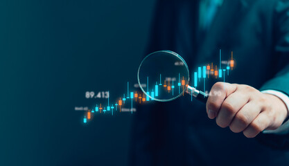hand holding a magnifying glass with graph stock market. Business finance investment fun forex and...