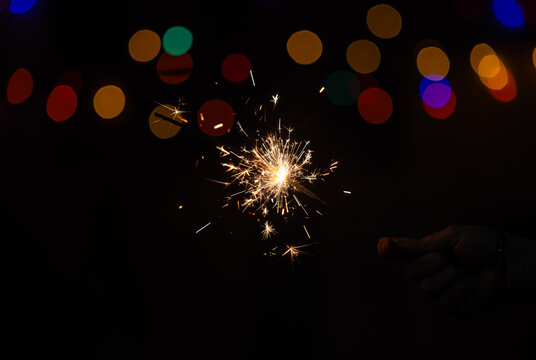 Sparkler or Fuljhadi in hand with dark black background with colorful bukeh to celebrate the festival of Diwali.