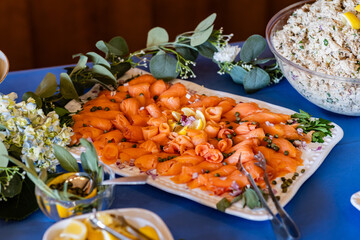 large platter of rolled smoked salmon garnished with lemon and capers, bowl of tuna salad