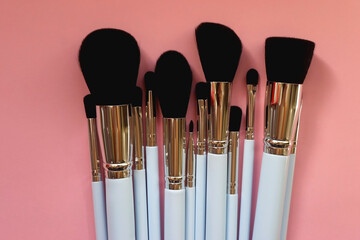 Various different make up brushes on pink background. Top view.