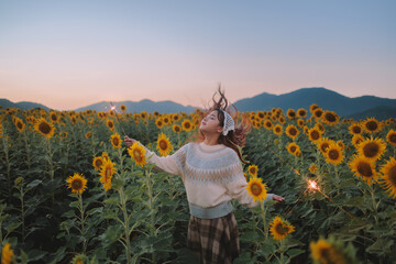 Woman playing sparkle  in sunflower field, nature