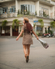 Girl holding flowers in hand crossing the road 