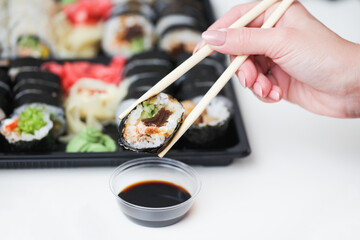 Sushi background. Woman hand holding chopsticks. Futomaki salmon roll. Japanese food isolated on...