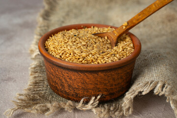 Flax seeds with a clay bowl close-up. - obrazy, fototapety, plakaty