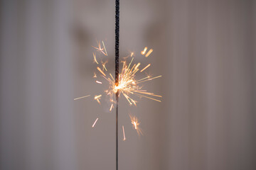 Sparkling sparkler with star and curtain in the background