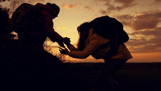 Climbers Silhouettes Stretch Their Hands To Each Other, Climbing To Top Of Hill. Team Of Businessmen, Victory. Lend Helping Hand. Travelers Climb One After Another On Rock. Teamwork Of Business People